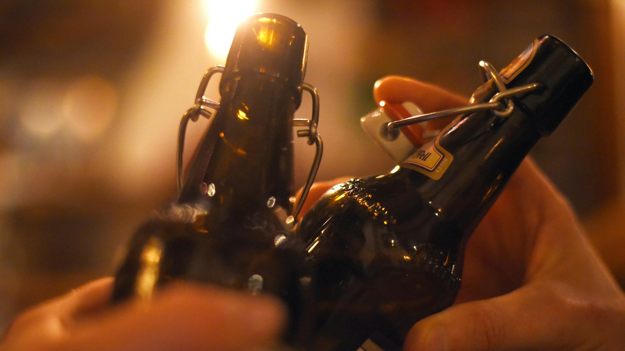 Das Symbolfoto zeigt zwei Bierflaschen mit Bügelverschluss, mit denen angestoßen wird.