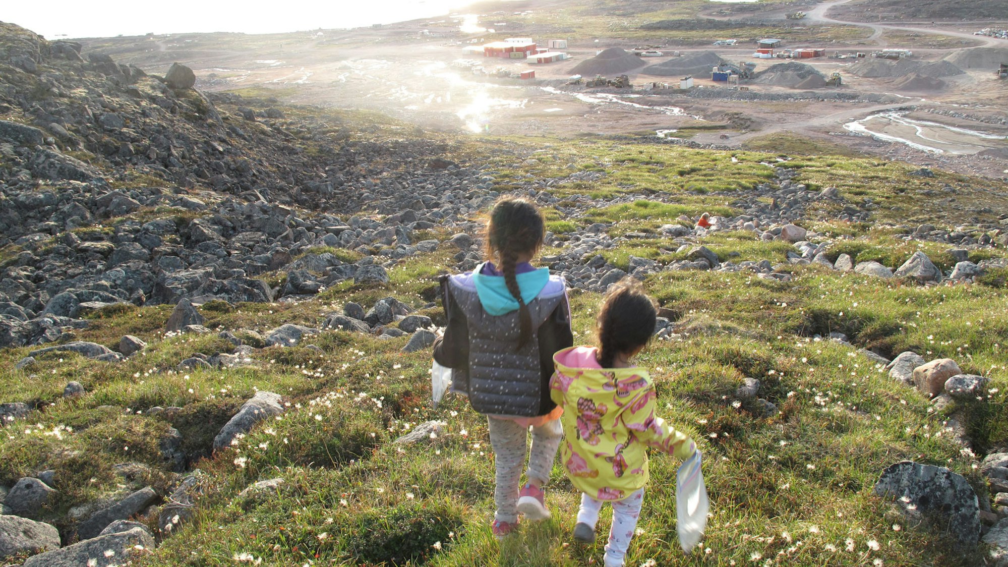 Inuit-Kinder laufen einen Berg hinunter.