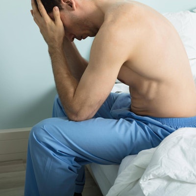 Mann sitzt auf dem Bett und zweifelt