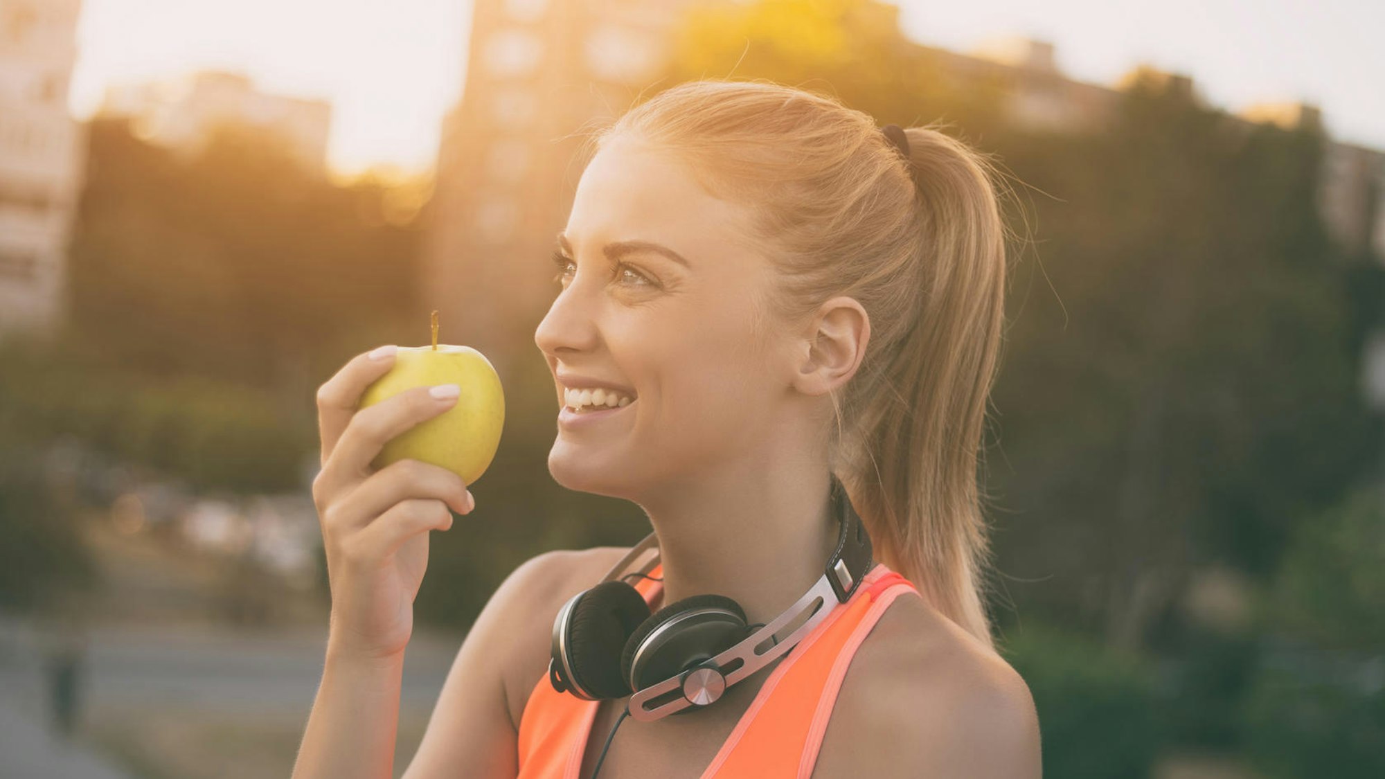 Eine Frau in Sportkleidung hält einen Apfel in der Hand.