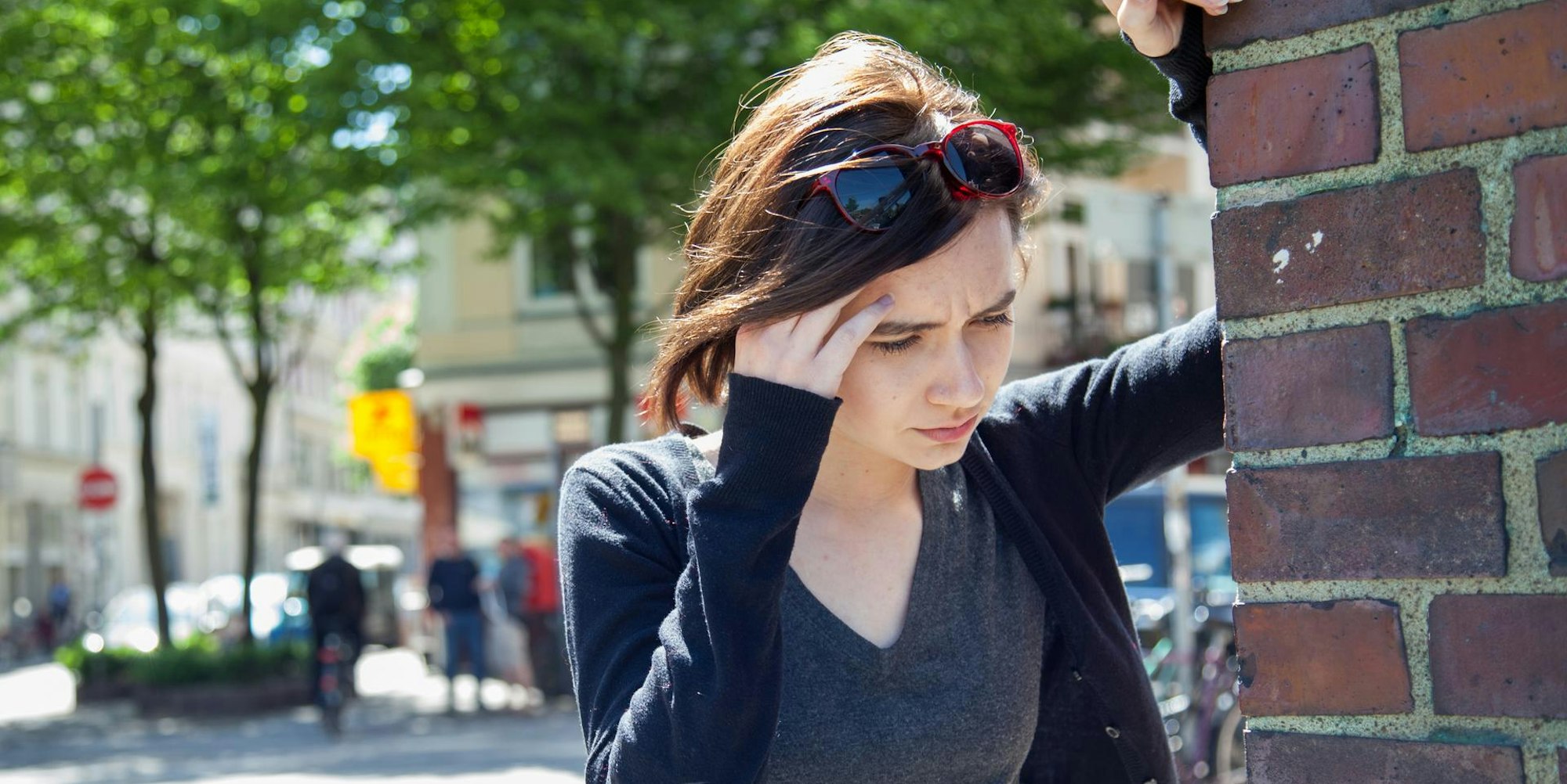 Frau hat Schwindel und hält sich an einer Hausecke fest