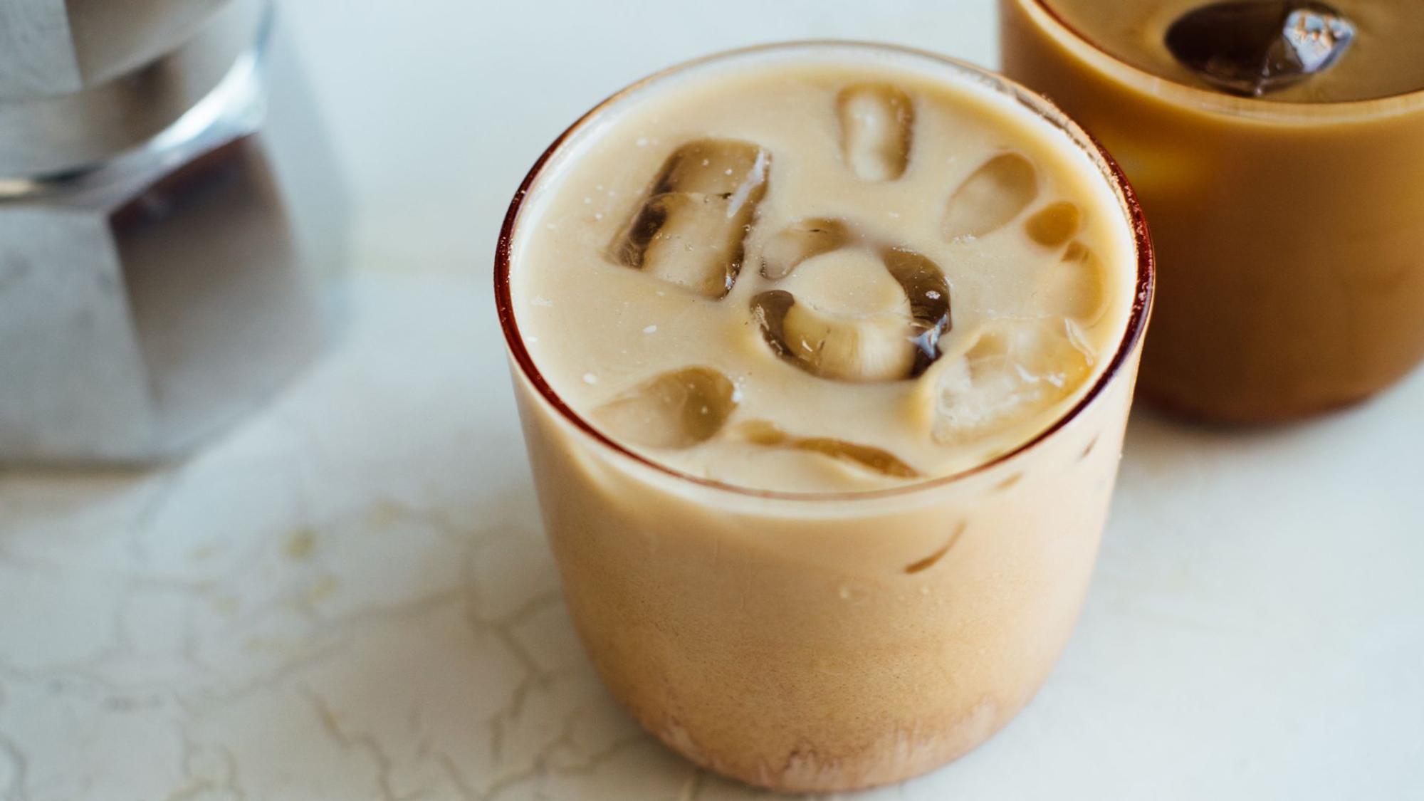 Ein Glas mit einem Haselnuss-Zimt-Latte steht angerichtet auf einem Tisch