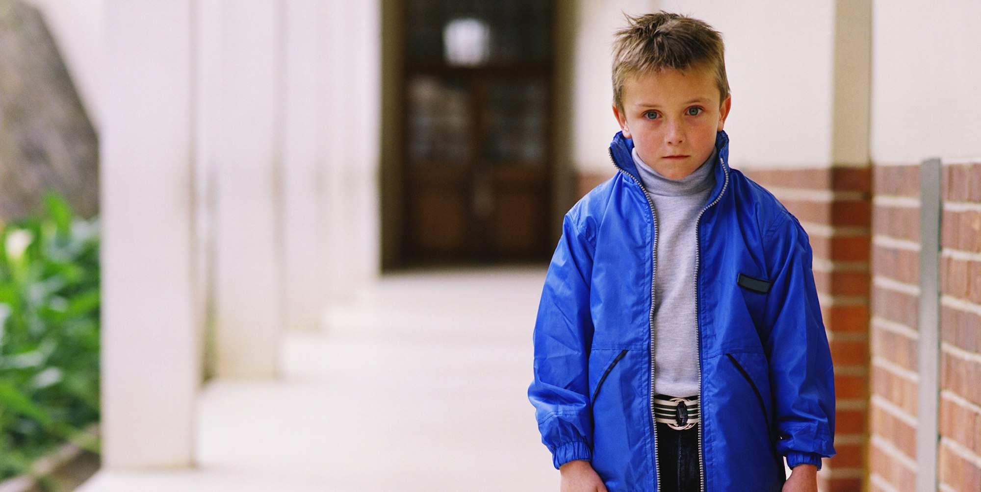 Ein Junge steht ängstlich im Schulflur.
