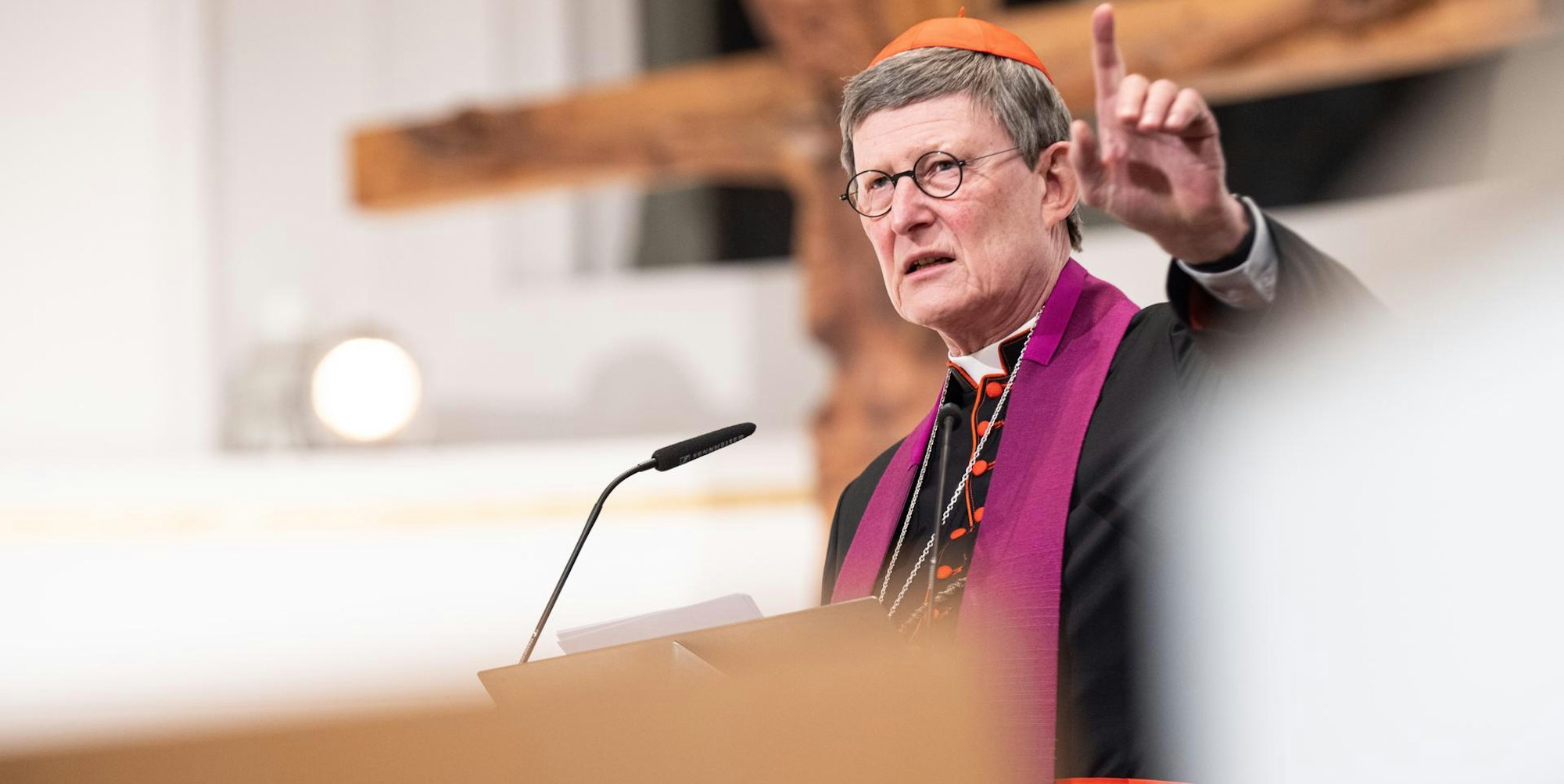 Kardinal Woelki steht vor einem Kreuz