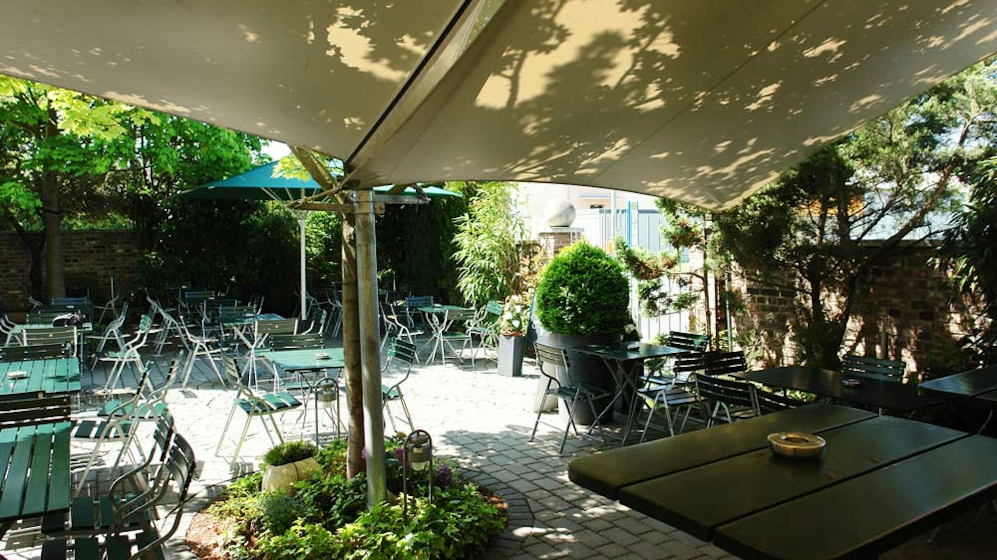 Mit Sonnensegeln überdachter grüner Innenhof im Wirtzhaus Wesseling