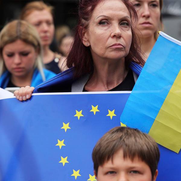 Eone Frau hält eine EU-Flagge und eine ukrainische Flagge in der Hand.