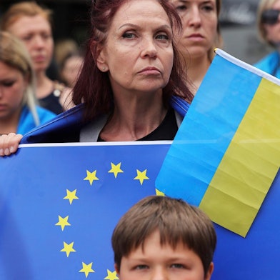 Eone Frau hält eine EU-Flagge und eine ukrainische Flagge in der Hand.