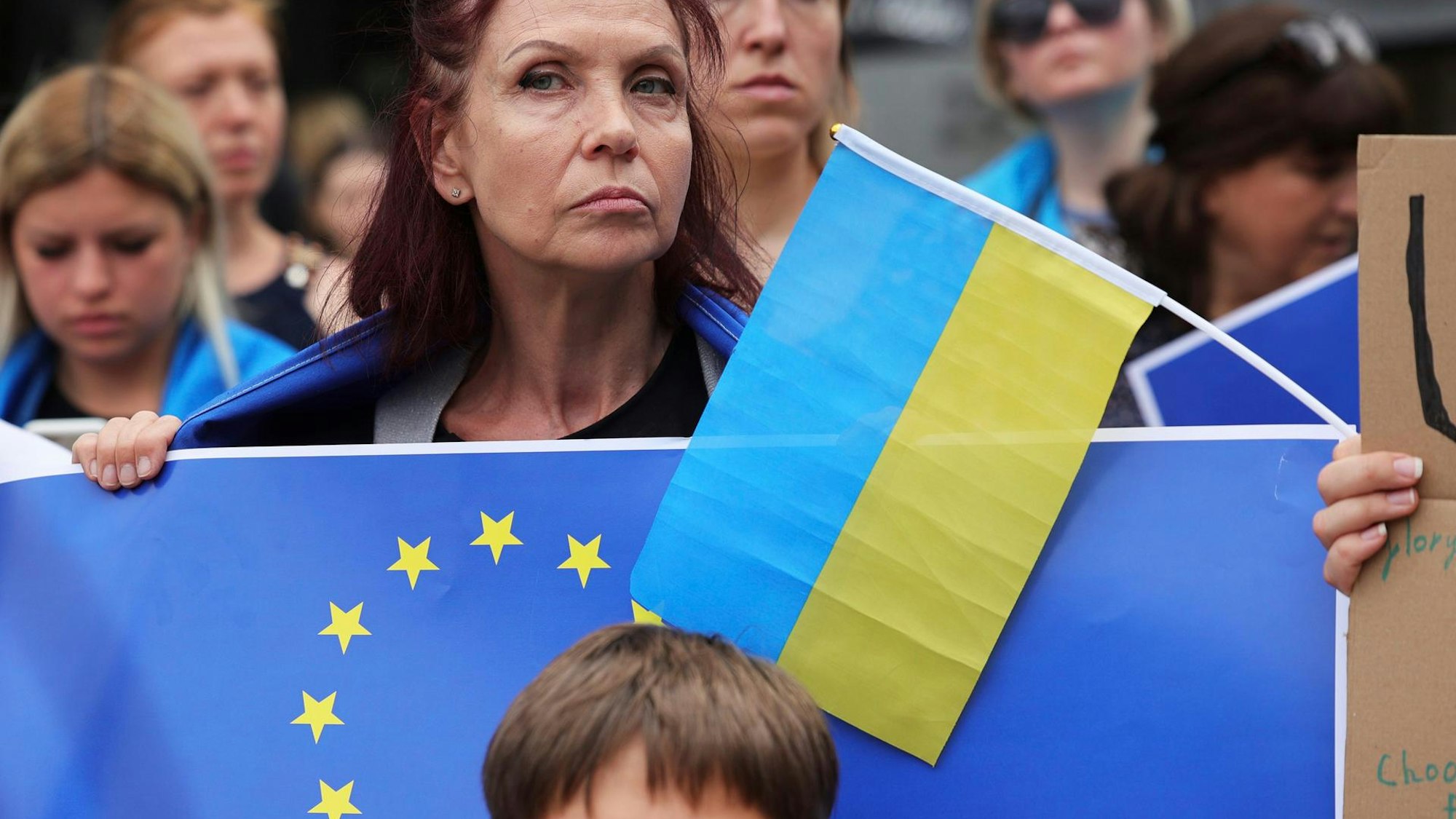 Eone Frau hält eine EU-Flagge und eine ukrainische Flagge in der Hand.