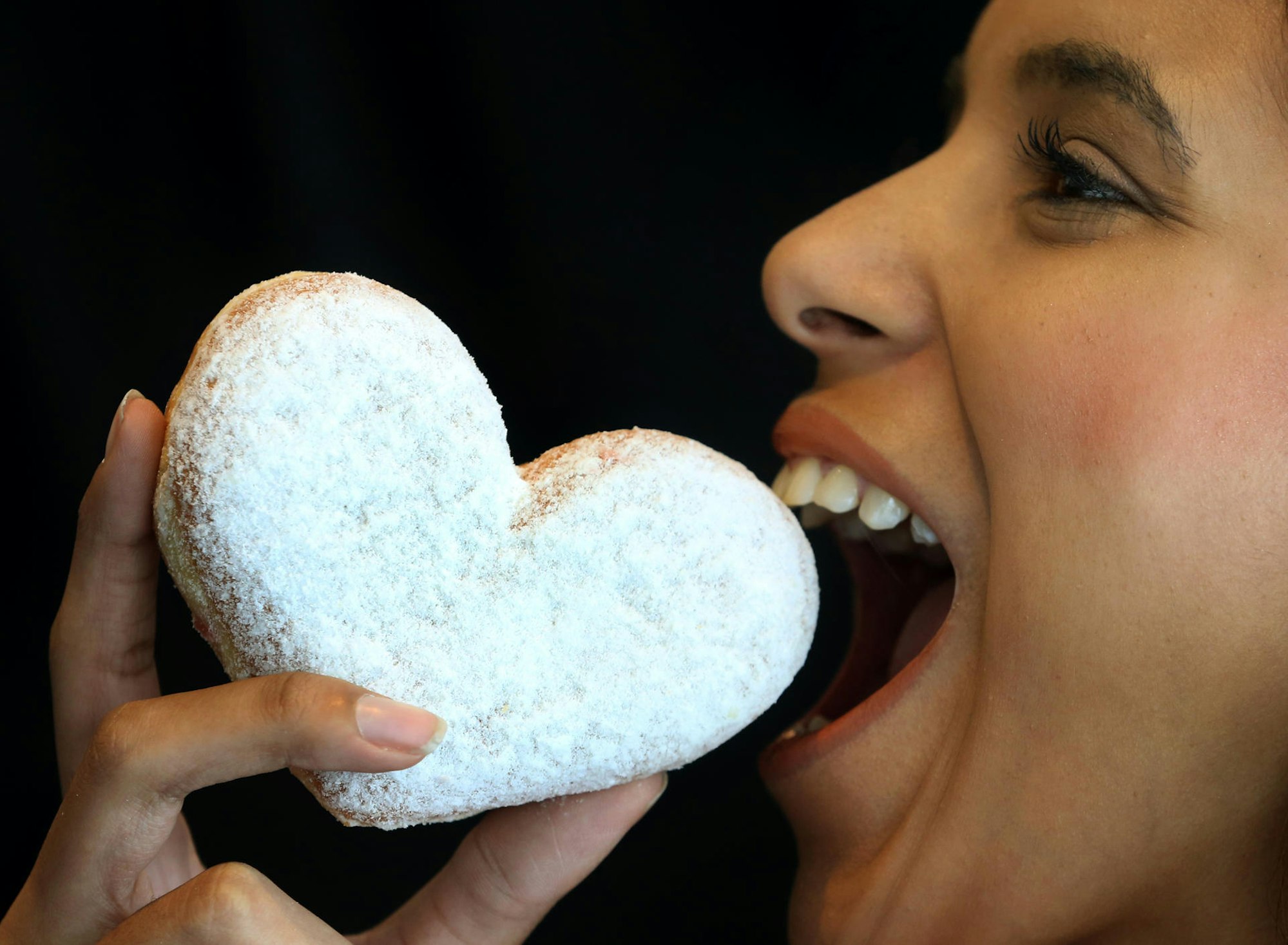 Frau beisst in Berliner Süßigkeit