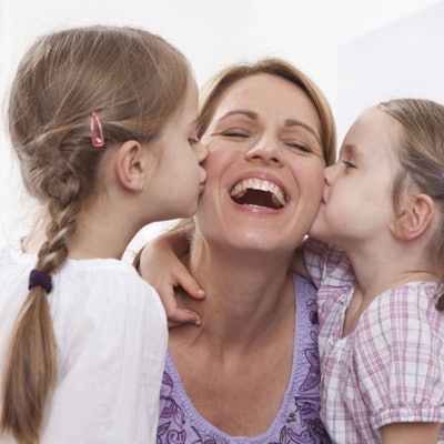 Mutter wird von ihren Töchtern geküsst.