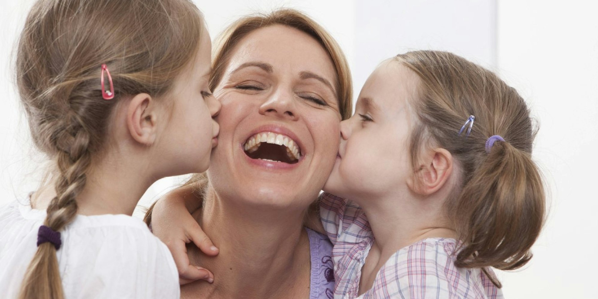 Mutter wird von ihren Töchtern geküsst.