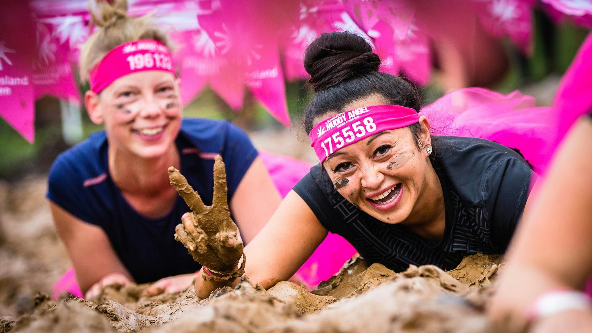 Zwei Teilnehmerinnen beim Muddy Angel Run Köln kriechen durch Schlamm.