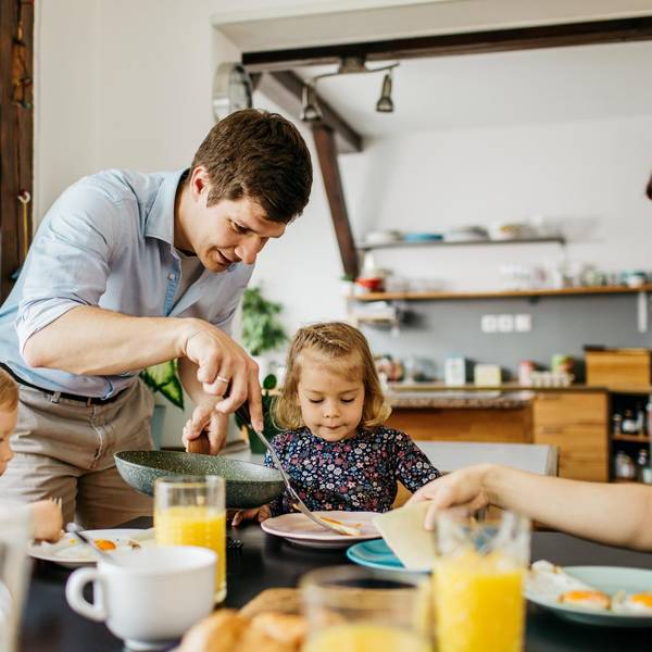 Eine Familie mit Vater, Mutter und zwei Kindern sitzt am Frühstückstisch