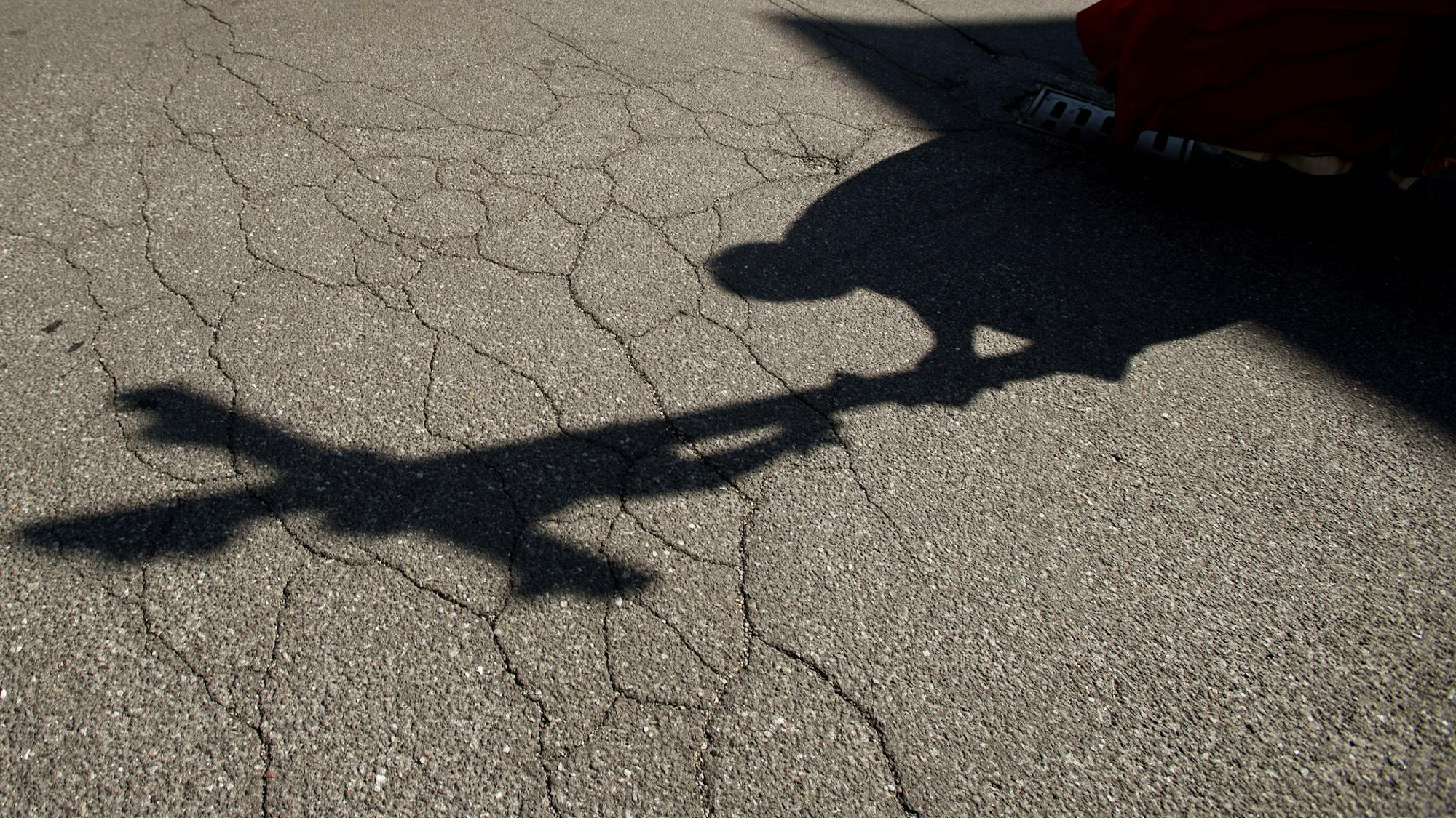 Ein Priester wirft einen Schatten auf dem Asphalt.