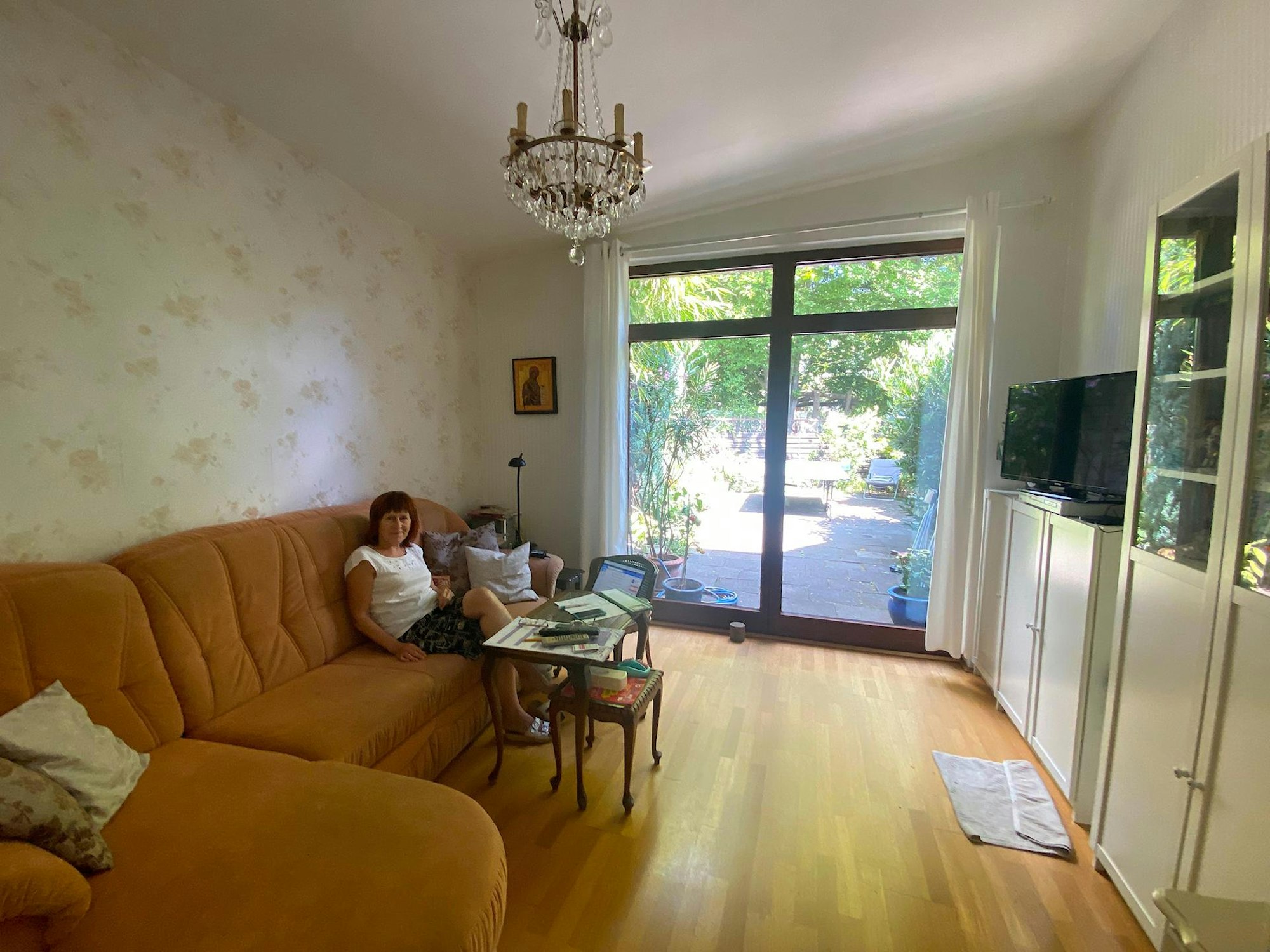 Galina sitzt auf dem Sofa. Im Hintergrund ist die Terrassentür zum Garten sichtbar.