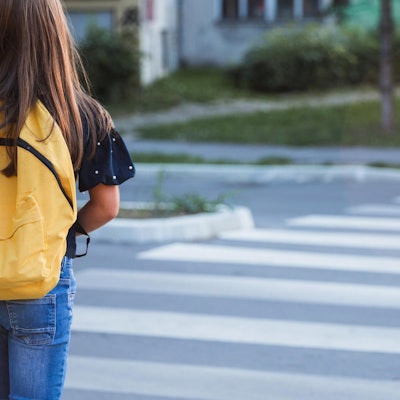 Ein Mädchen geht über die Straße.