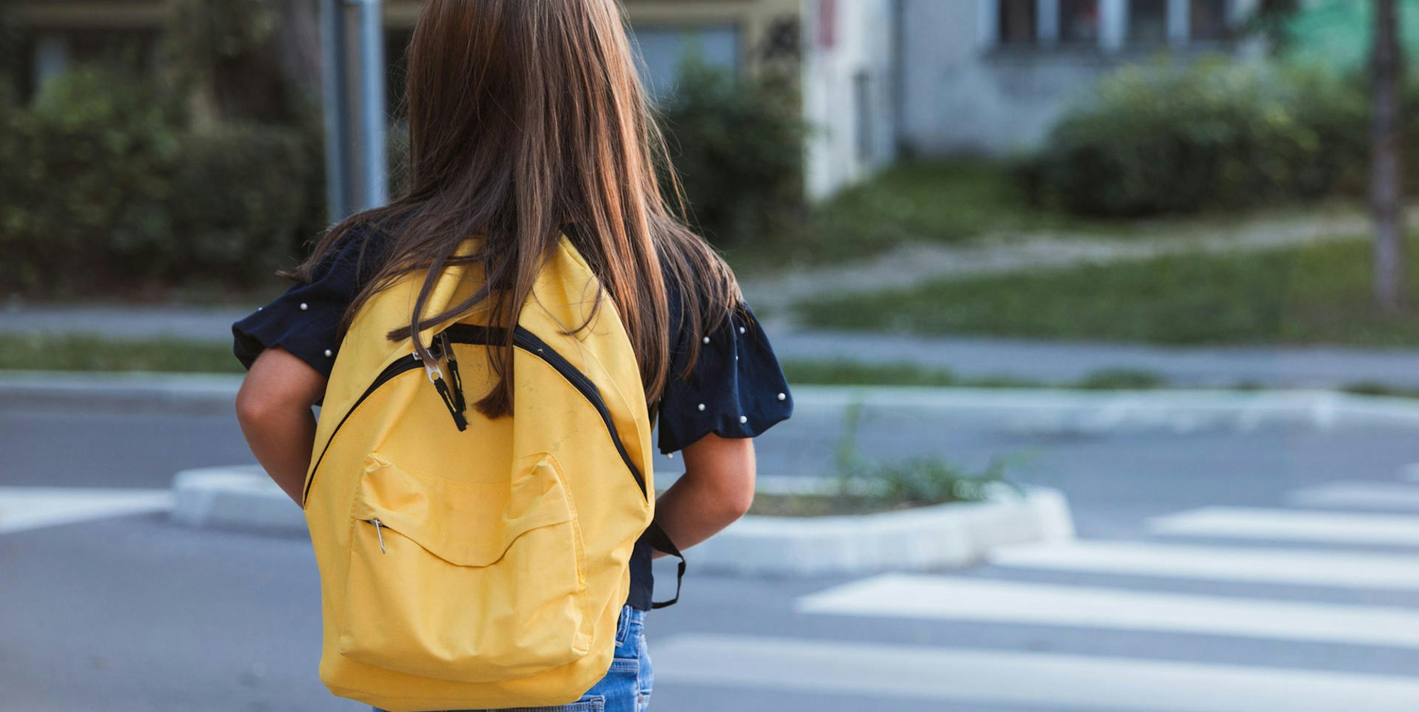 Ein Mädchen geht über die Straße.