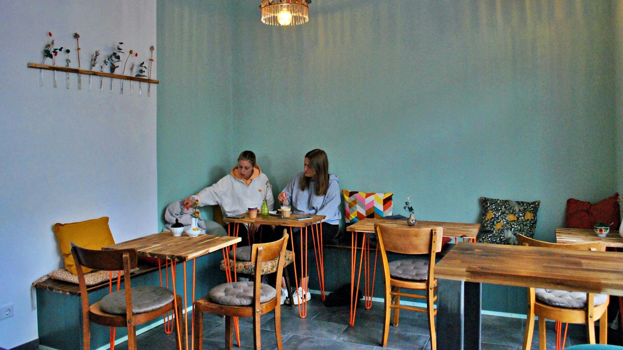 Zwei junge Frauen sitzen in der Ecke eines Cafés.