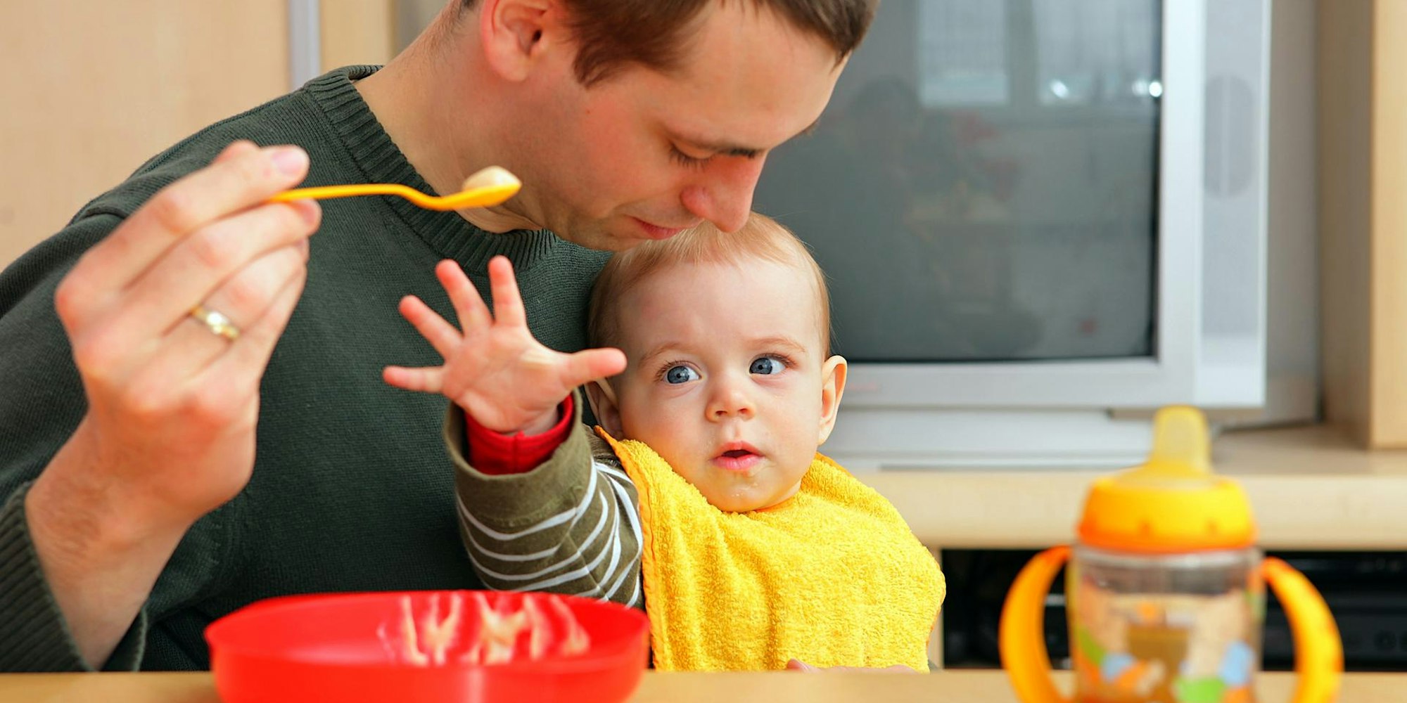 Vater füttert Baby