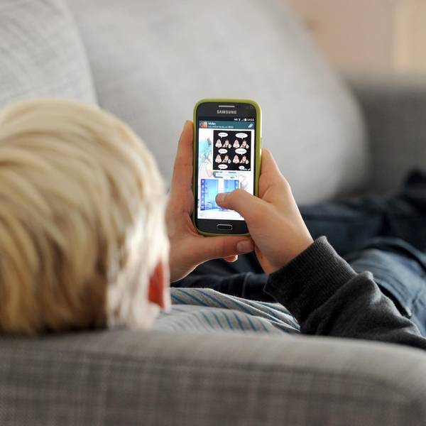 Junge liegt mit Smartphone auf dem Sofa