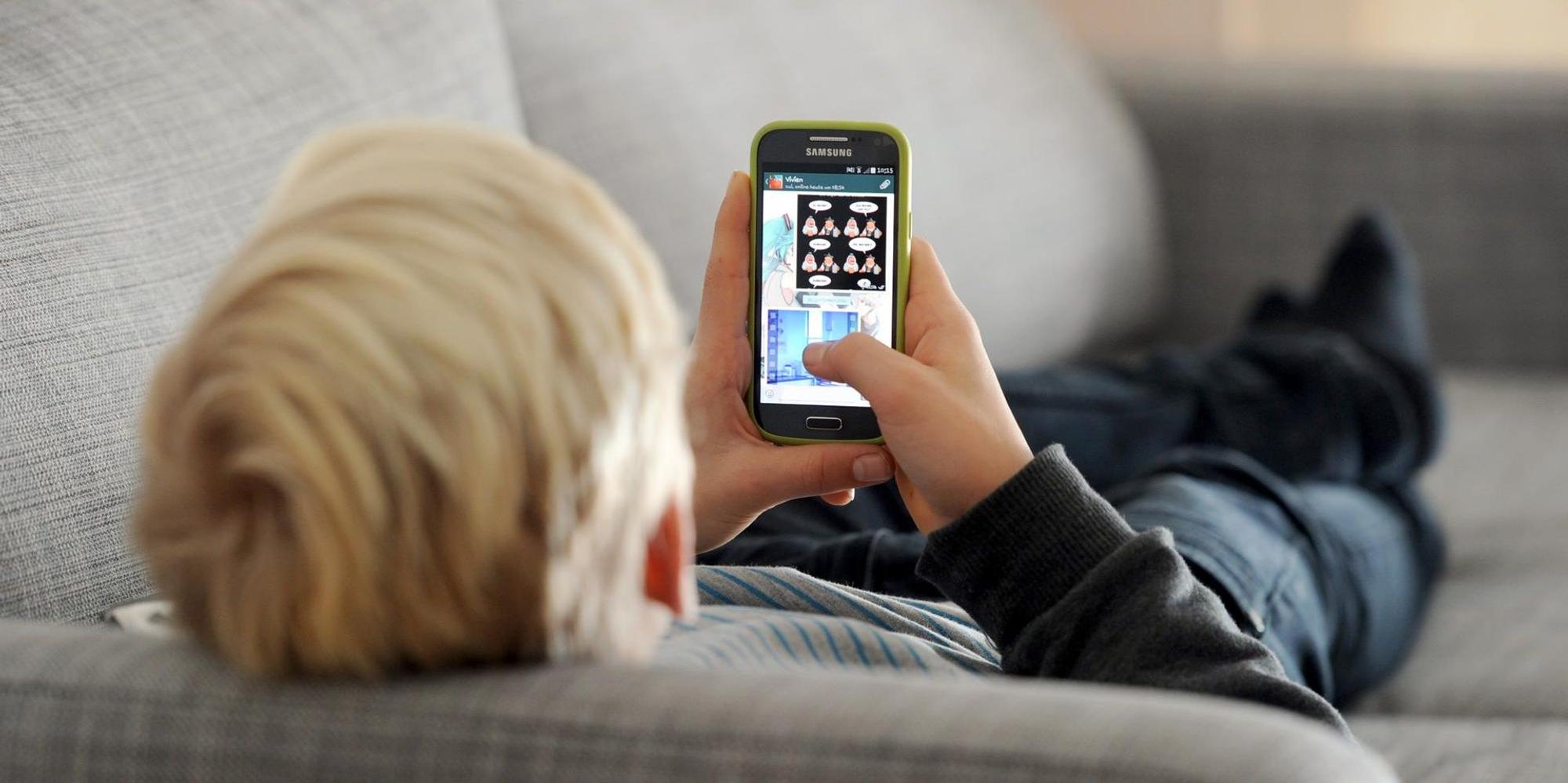 Junge liegt mit Smartphone auf dem Sofa