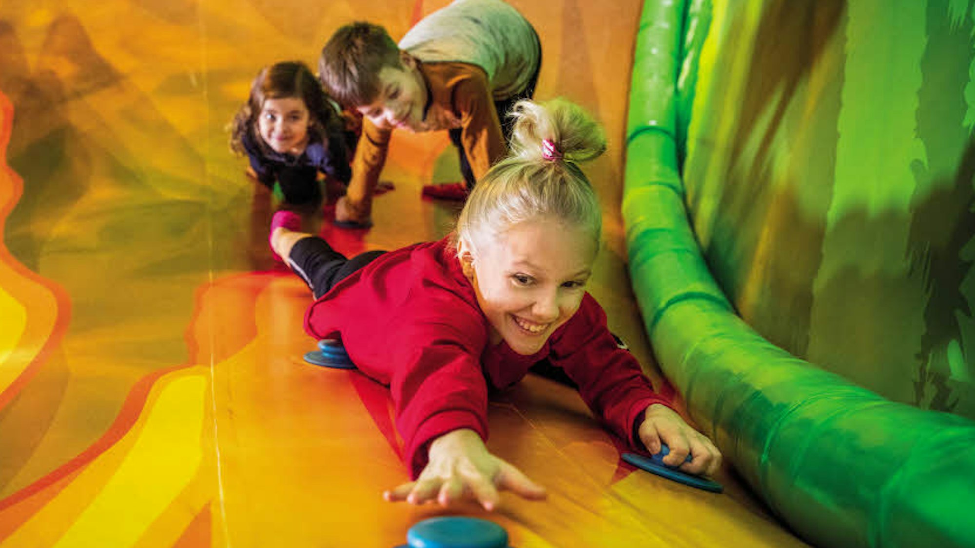 Drei Kinder in einer Rutsche im Indoor-Spielplatz HopLop in Pulheim.