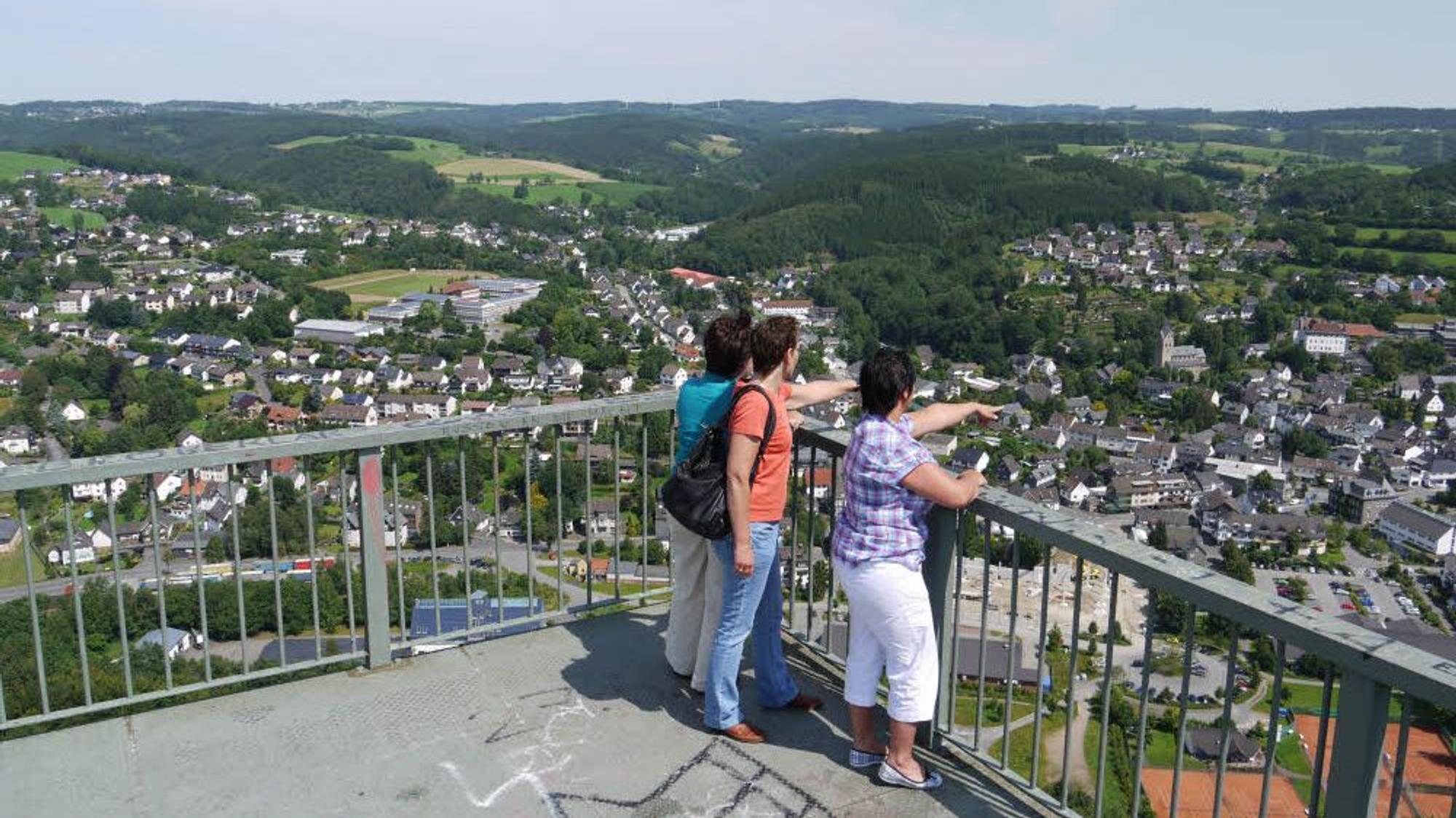 Menschen stehen auf einem Aussichtspunkt und schauen in ein Tal.