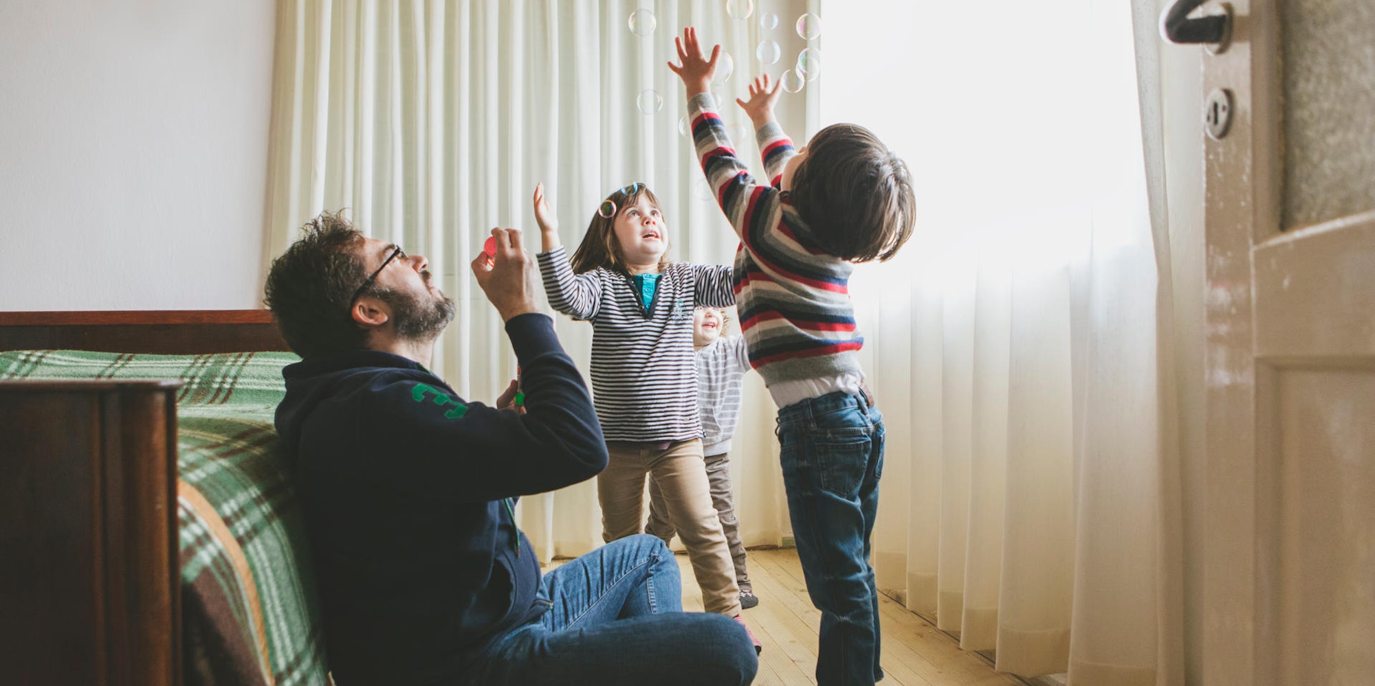 Ein Vater macht mit seinen Kindern Seifenblasen.