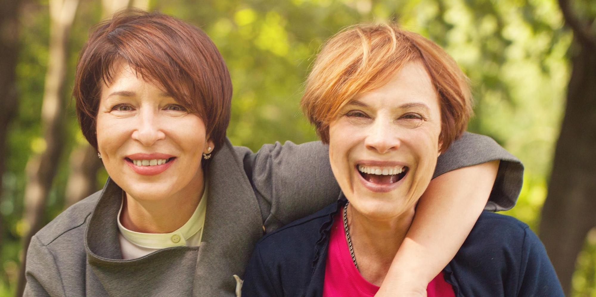 Zwei Frauen mittleren Alters lachen miteinander.