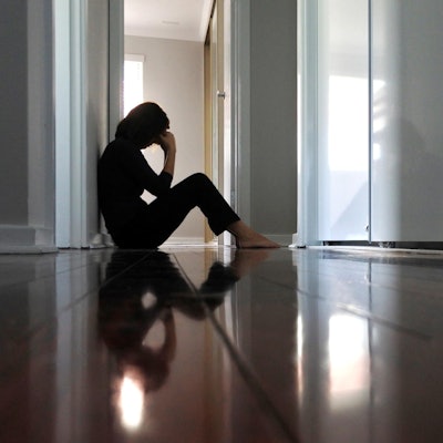 Frau sitzt alleine im Flur Getty