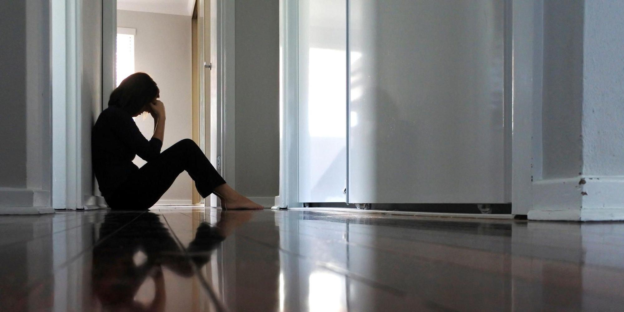 Frau sitzt alleine im Flur Getty