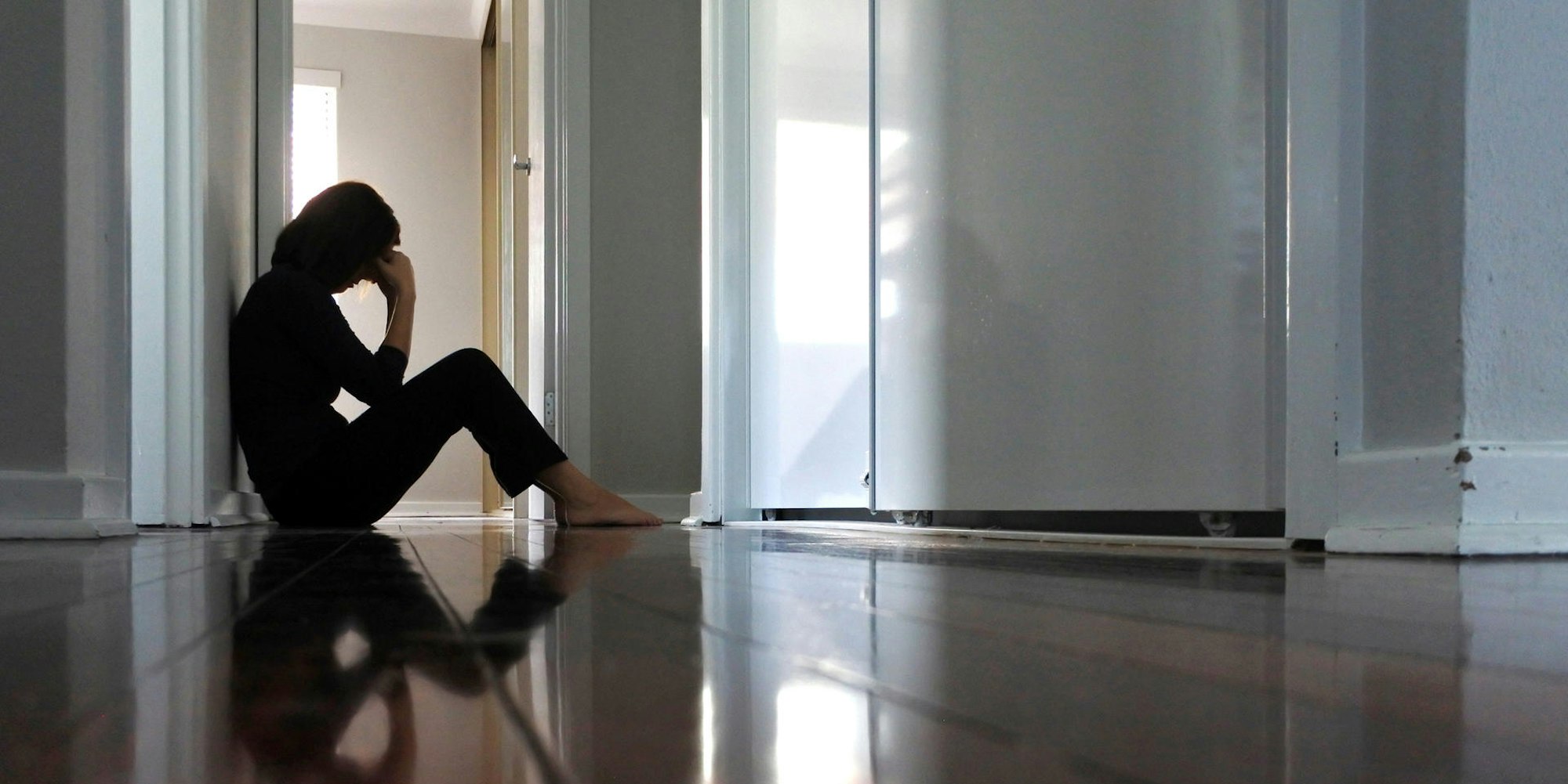 Frau sitzt alleine im Flur Getty