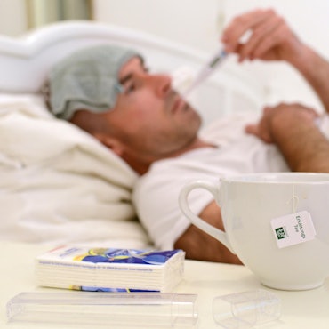 Mann liegt kranj mit Grippe oder Erkältung im Bett dpa