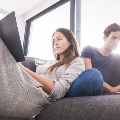 Mann_und_Frau_sitzen_mit_eigenem_Laptop_auf_dem_Sofa