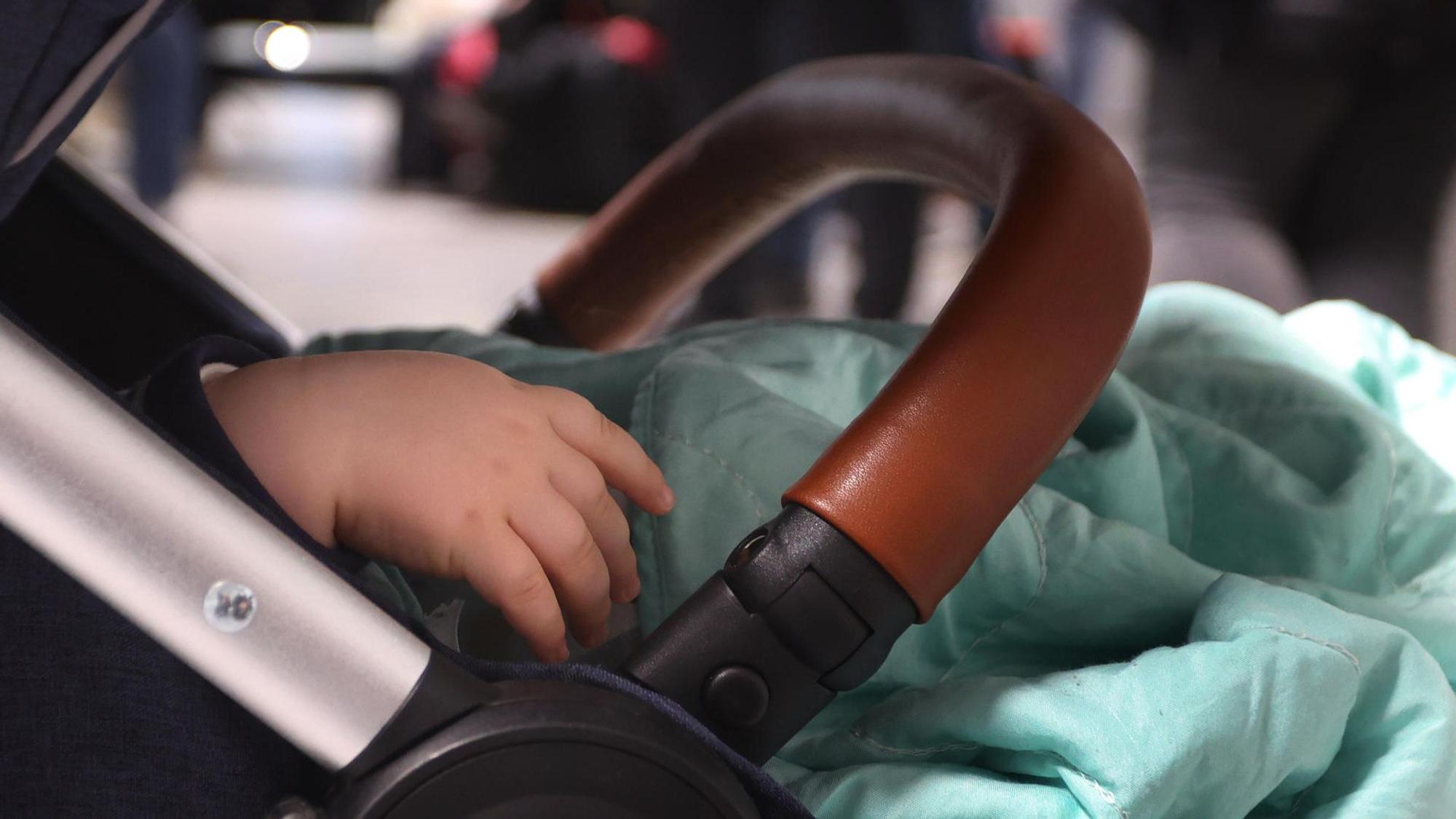 Ein Kind liegt in einem Kinderwagen.