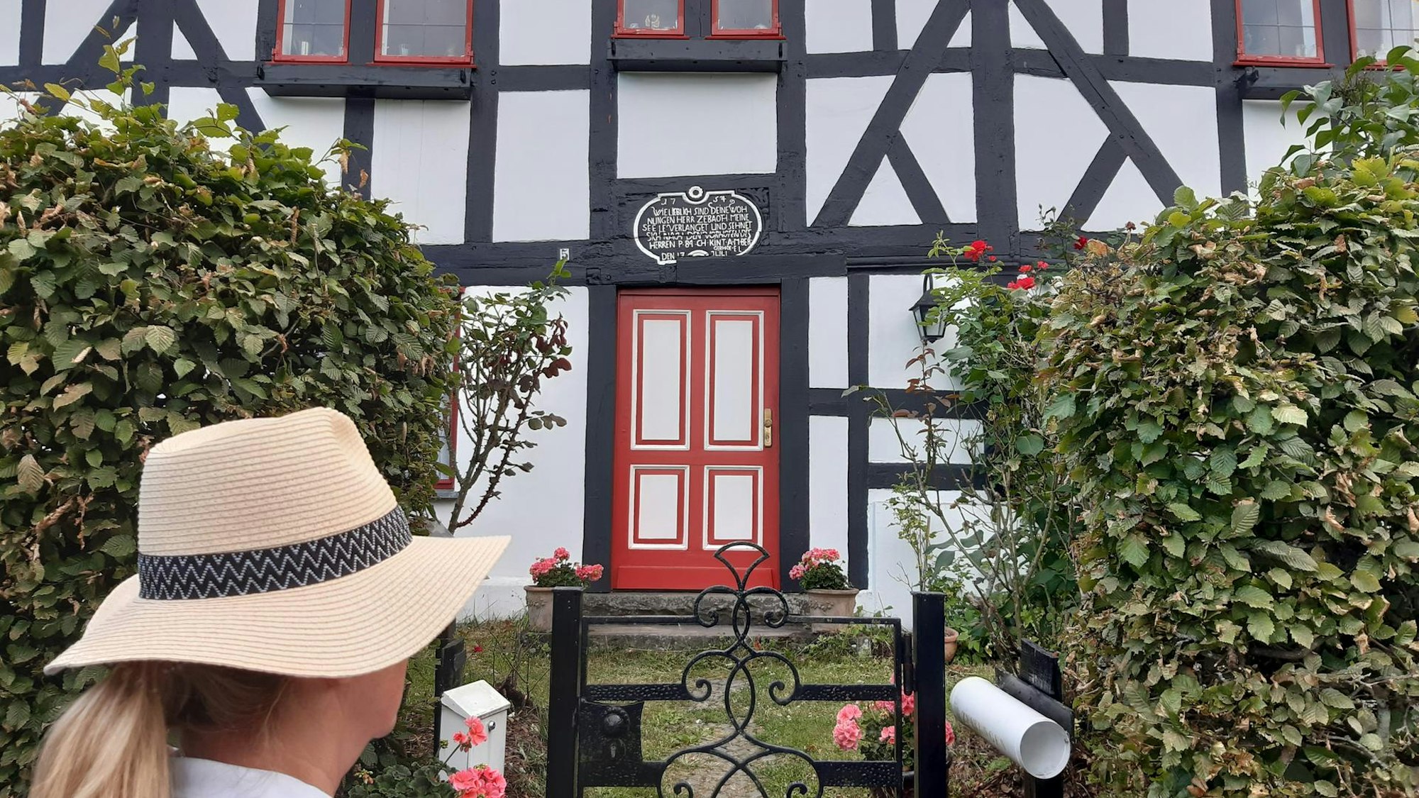 Eine Frau steht vor der toten Tür eines Fachwerkhauses.
