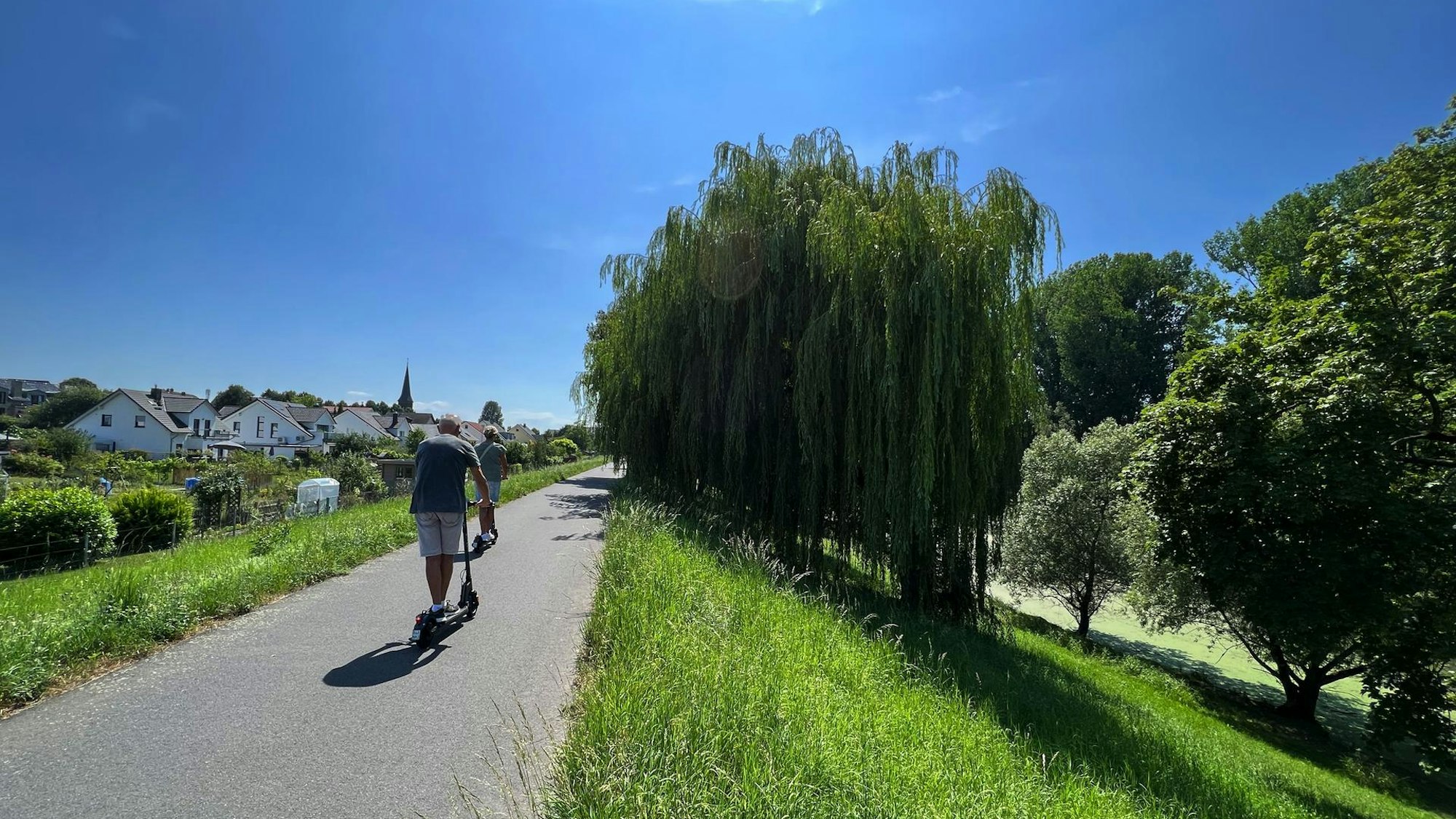 Mann fährt mit einem E-Scooter auf einem Deich