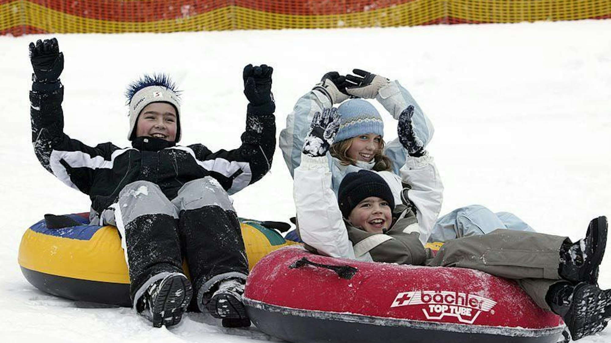 Kinder liegen auf Reifen im Schnee