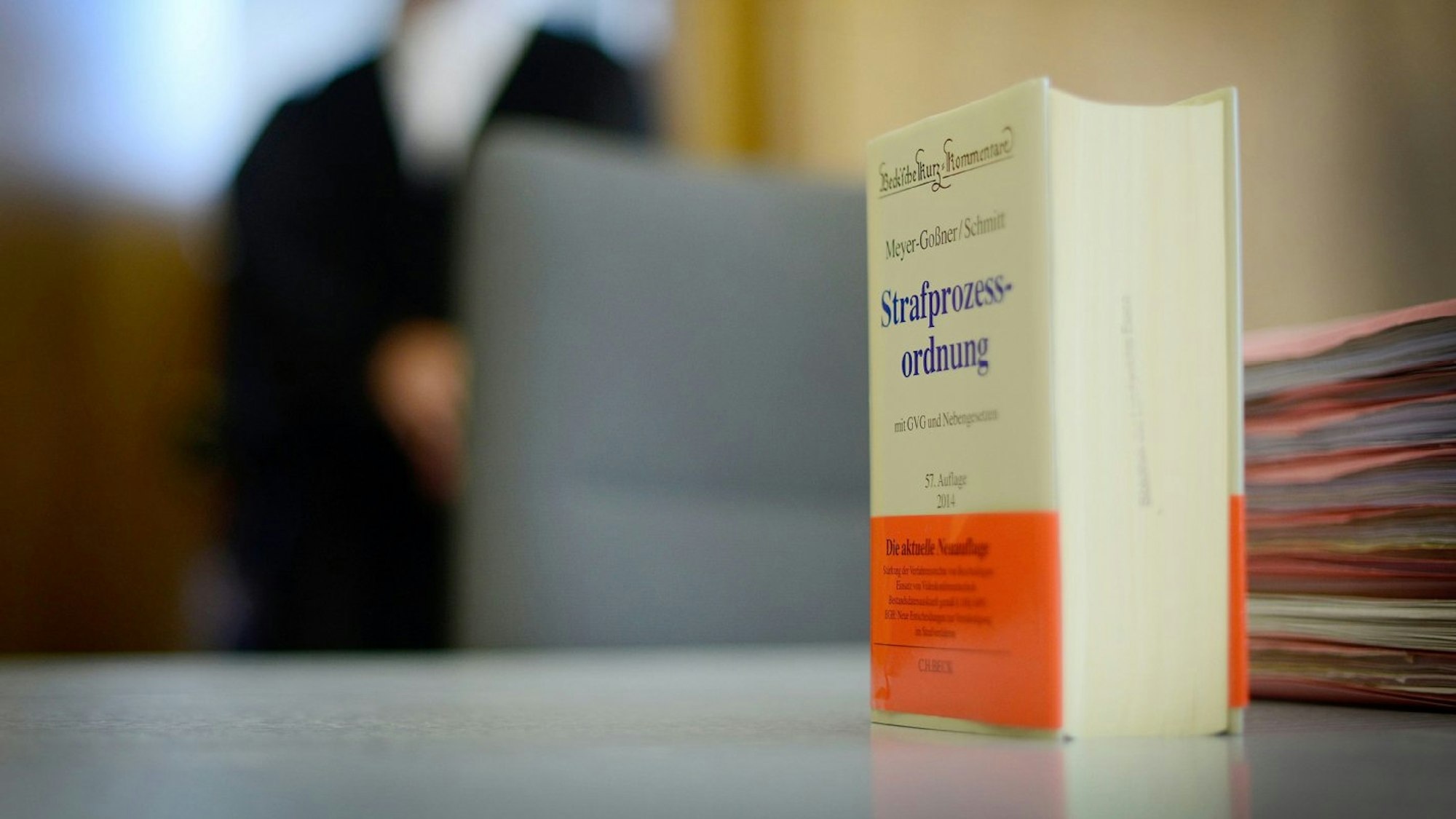 Die Strafprozessordnung steht auf einem Schreibtisch, daneben liegt ein Stapel Akten.