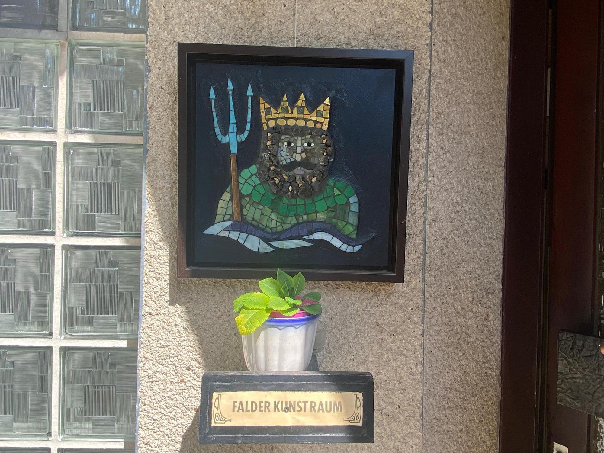 Neben einer Haustür hängt ein Mosaik, das Poseidon darstellt.