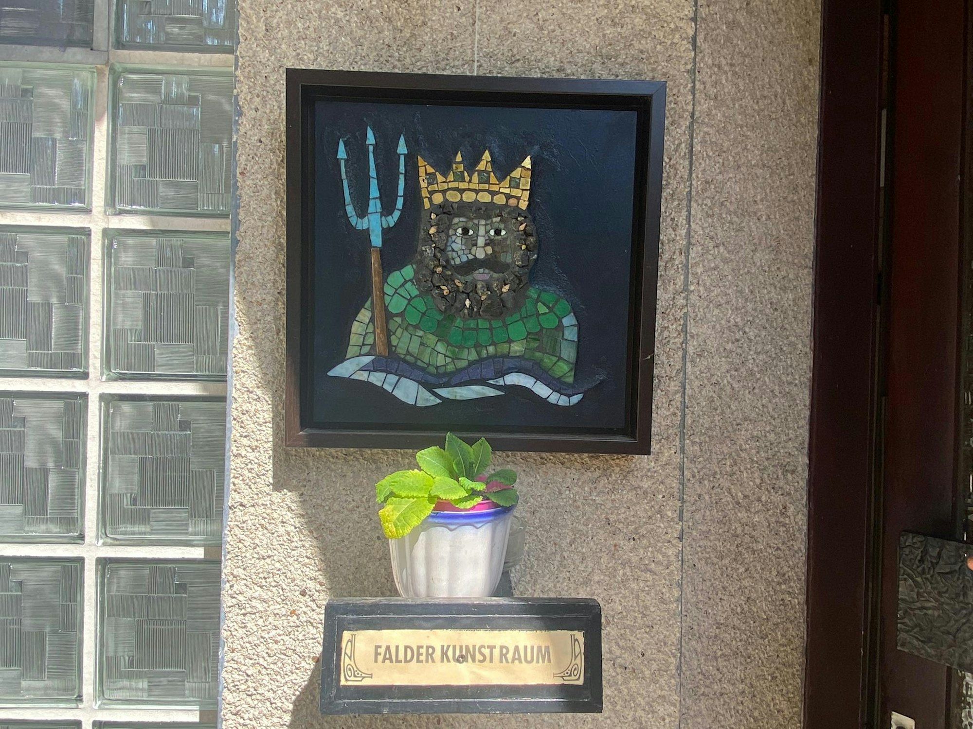 Neben einer Haustür hängt ein Mosaik, das Poseidon darstellt.