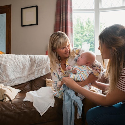 Oma nimmt der Mutter das Baby ab.