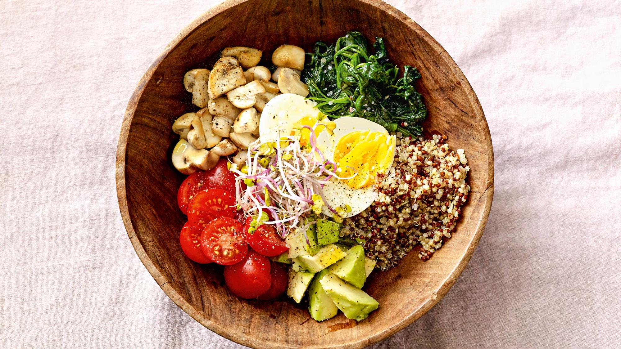 Eine herzhafte Breakfast Bowl mit Pilzen, Eiern und Gemüse, angerichtet in einer Holzschale