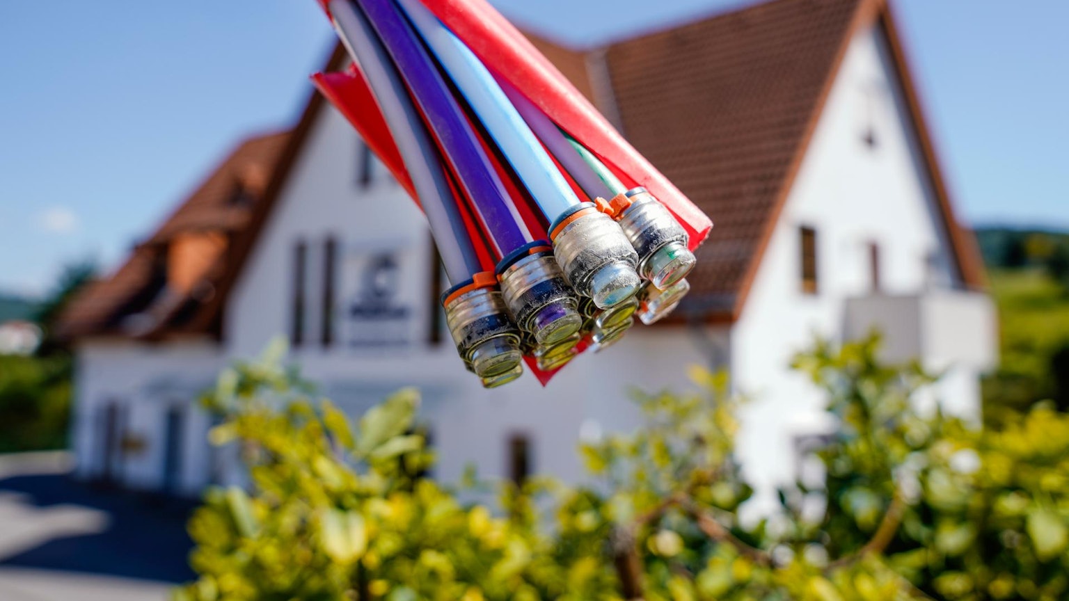 Bunte Glasfaserkabel sind vor einem Haus zu sehen.