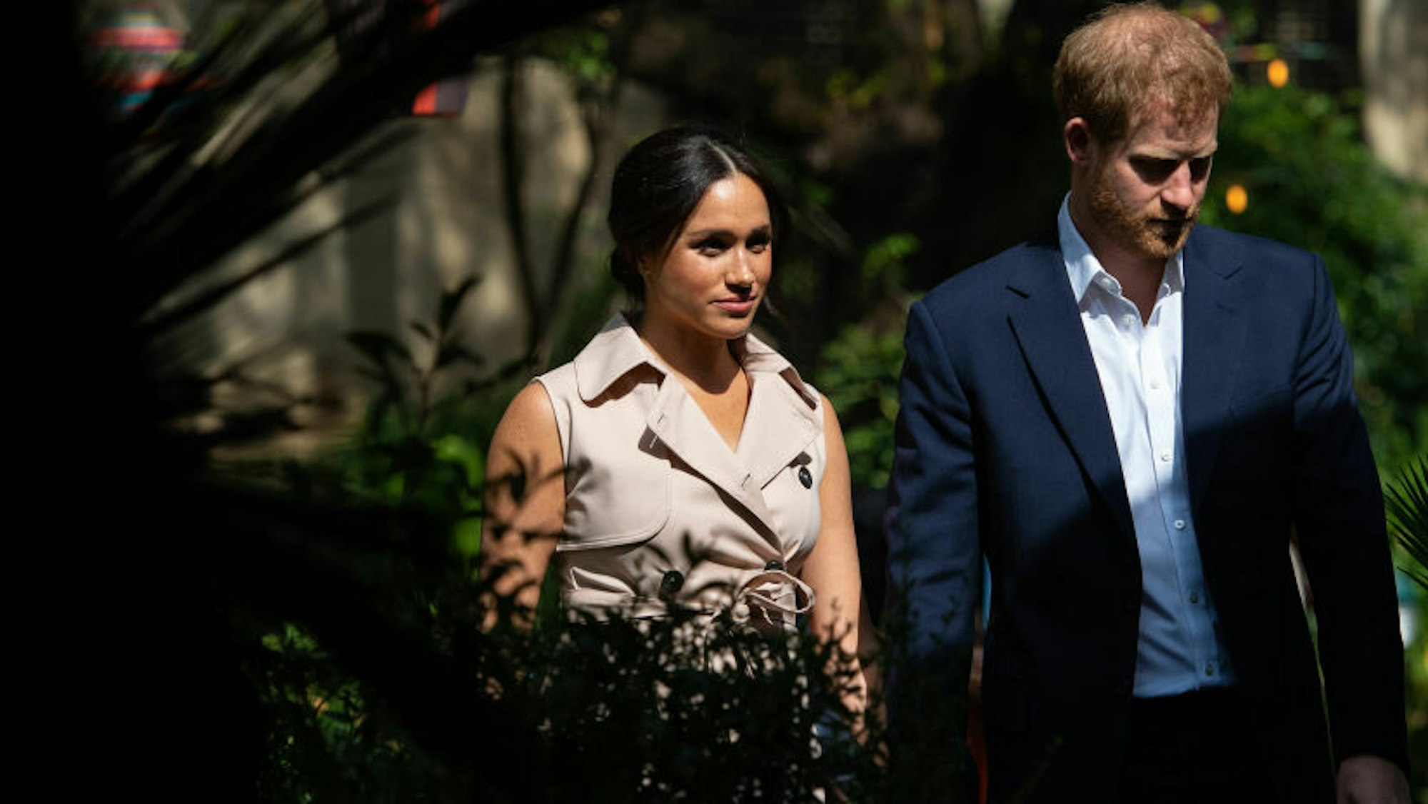 Meghan und Harry spazieren durch einen Garten.