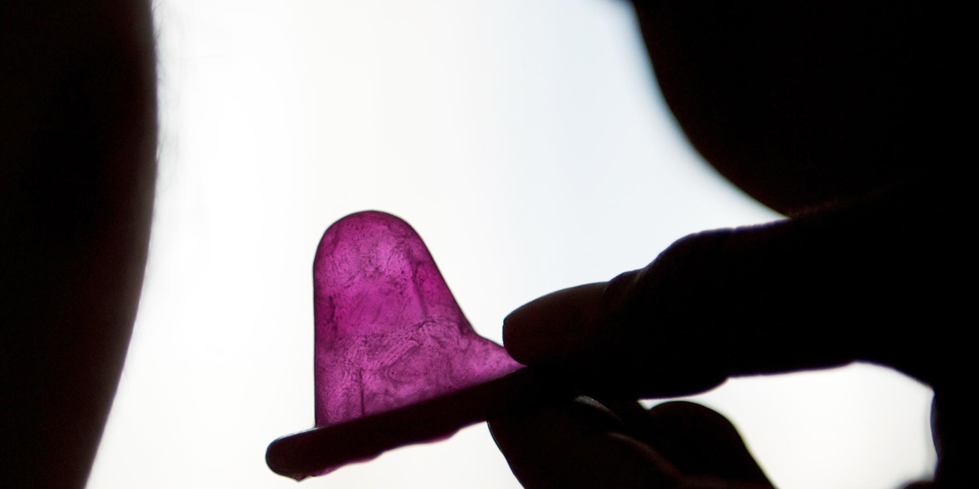 Eine Schatten-Hand hält ein Kondom