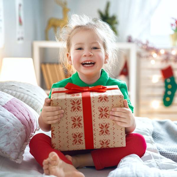 Ein Mädchen hält lachend ein Geschenk in den Händen.