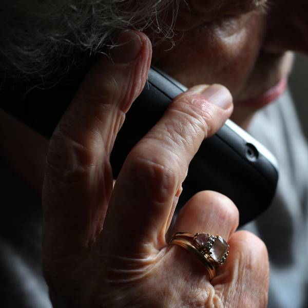 Das Symbolbild zeigt eine ältere Frau mit einem Telefonhörer in der Hand.