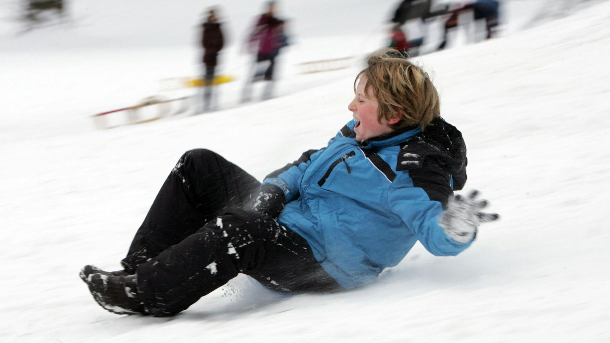 Ein Kind rutscht einen Hang hinunter.