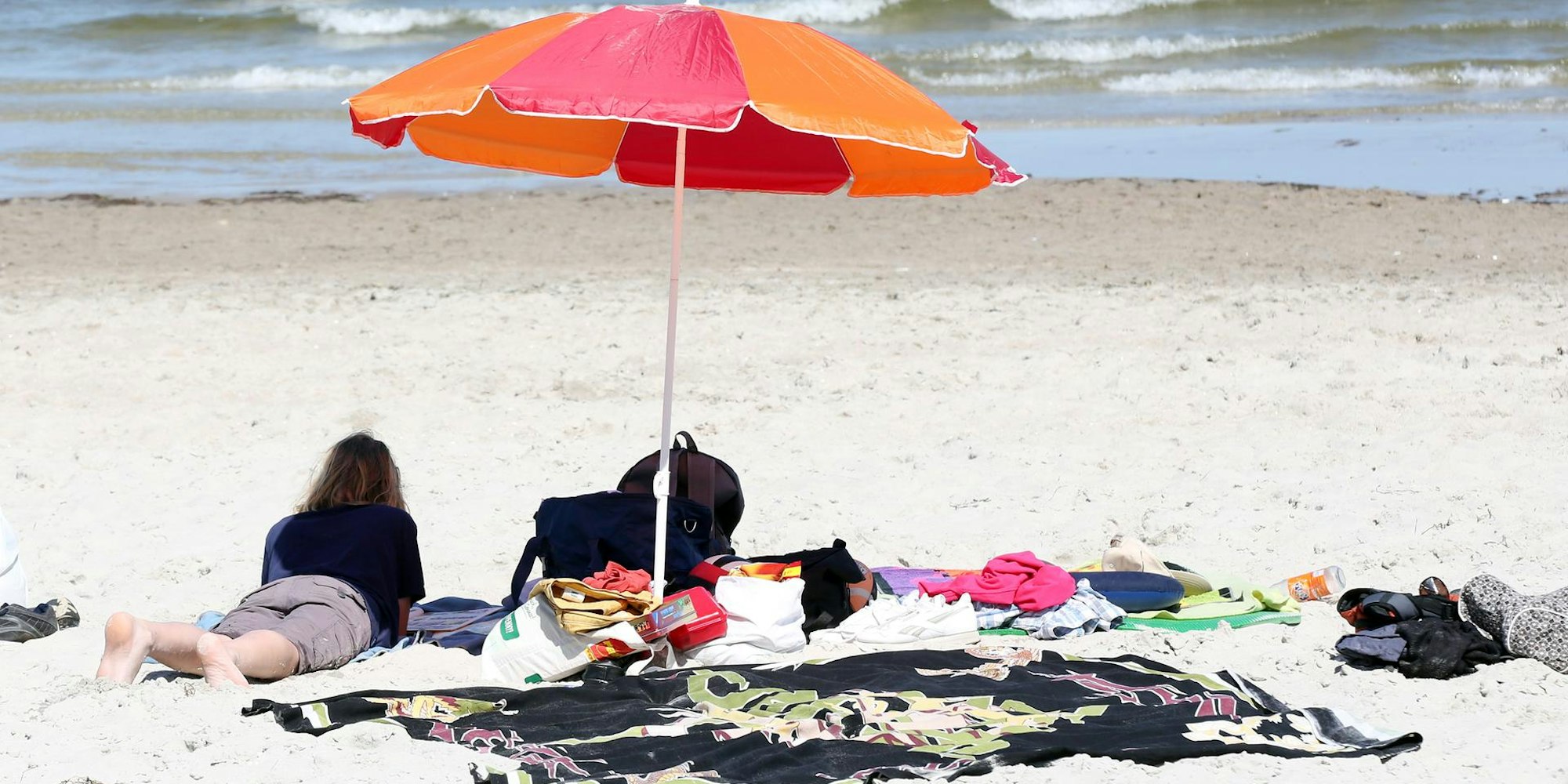 Frau liegt am Strand unter Sonnenschirm